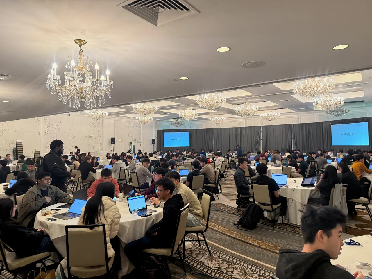 Competitors trading on laptops in the hotel ballroom