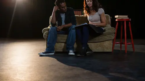 Actors reading their scripts on stage