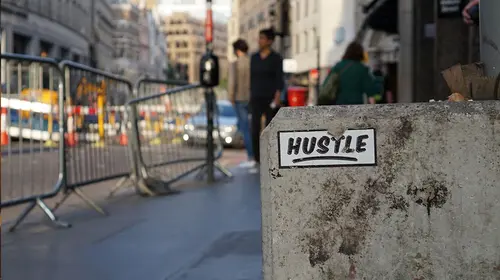 sticker of "Hustle" in front of city people 