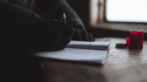 Man writing in a journal by the window